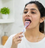 Dentist demonstrating tongue cleaning technique for better oral health and fresh breath